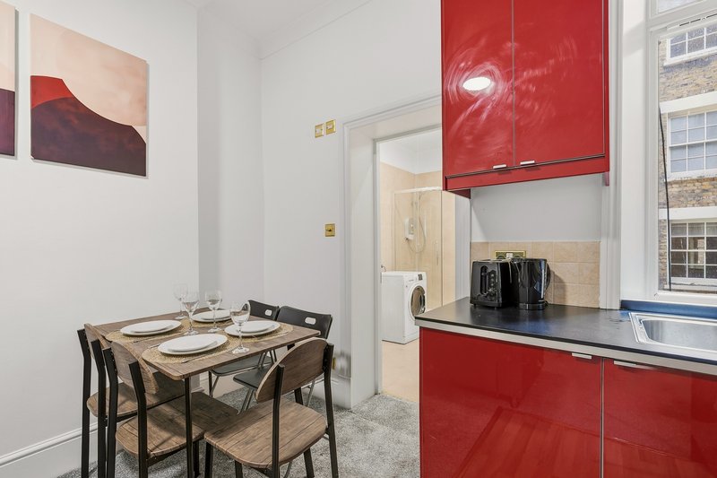 Modern kitchen with red cabinetry, dining table, chairs and window view