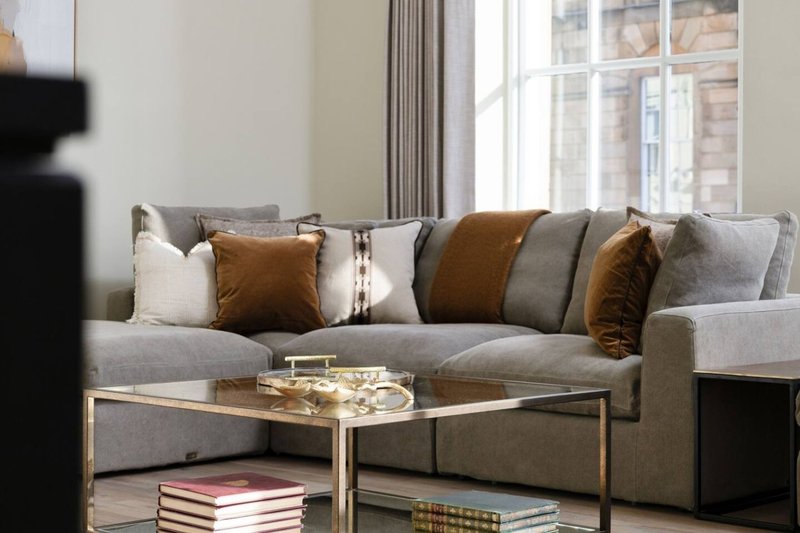 Modern living room with gray sofa, decorative pillows, glass coffee table and city view windows