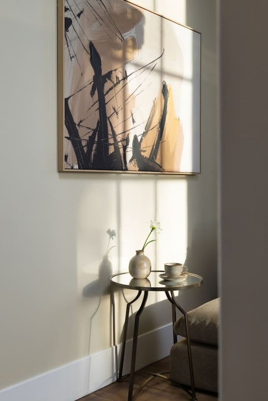 Corner nook with small round table, vases with flowers, framed abstract artwork on wall