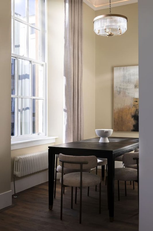Dining room with black table, chairs, large window, pendant light and wall art
