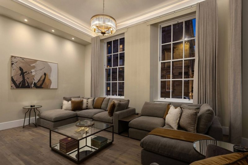 Modern living room with grey sectional sofa, large windows, pendant light and glass coffee table