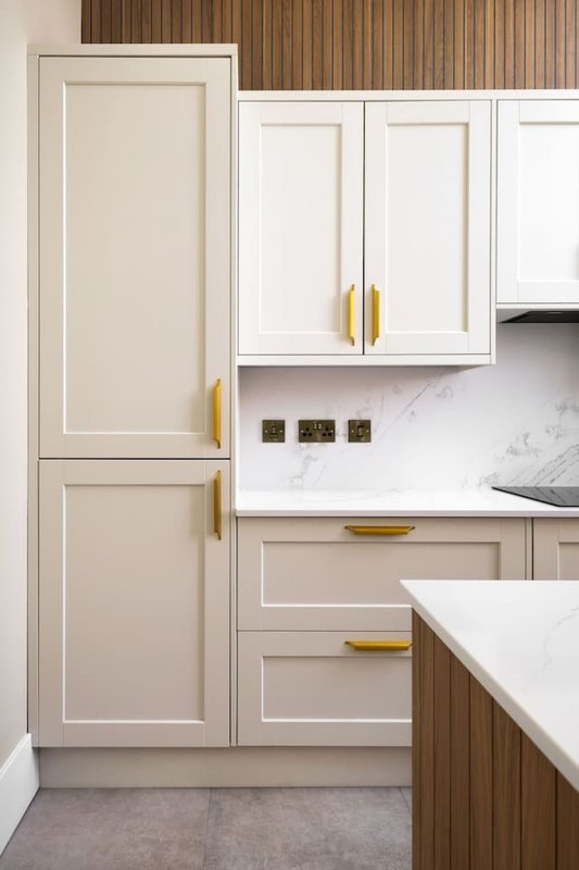 Modern kitchen with cream and wood cabinetry, marble countertop, and brass handles