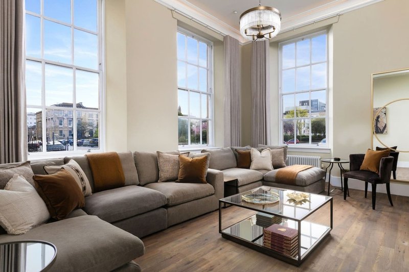 Spacious living room with grey corner sofa, large windows, wooden flooring and city views