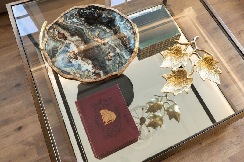 Glass display case with decorative items including shell dish, burgundy book, and gold leaf arrangement