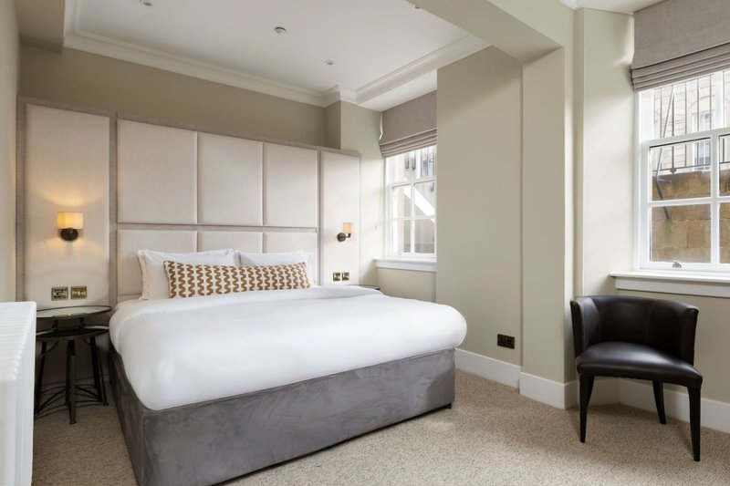 Modern bedroom with double bed, upholstered headboard, bedside lamps and black armchair