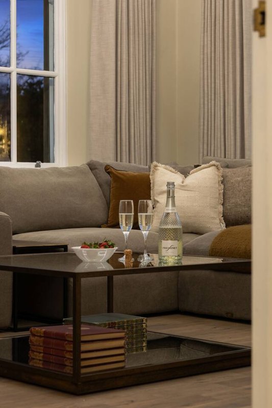 Modern living room with grey sofa, cushions, dark coffee table and evening window view