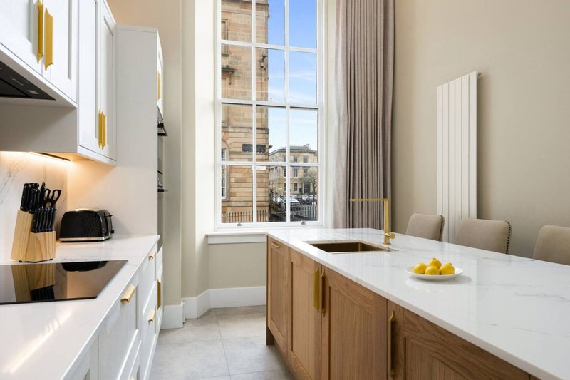 Modern kitchen with white cabinets, wooden island, marble countertop and city views