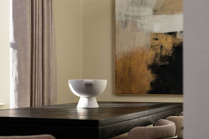 Modern living room with black console table, white sculptural bowl, and abstract artwork on wall