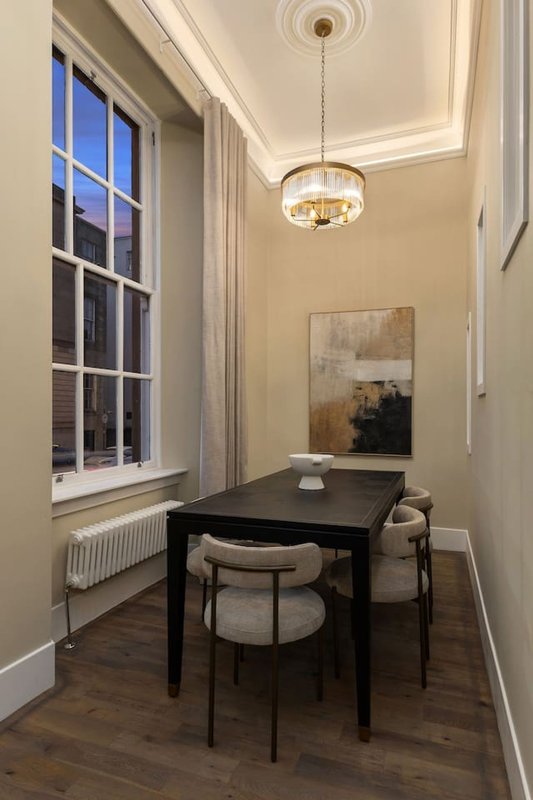 Modern home office with black desk, upholstered chairs, pendant light and window