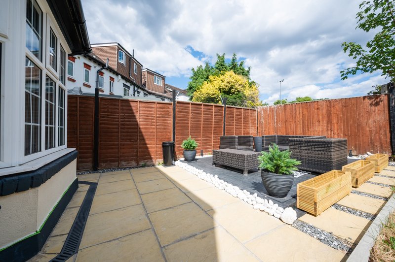 Rear garden patio with wooden fence, seating area, potted plants and wooden decking
