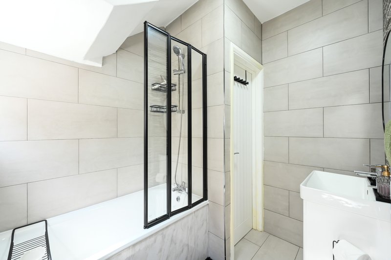 Modern bathroom with white subway tiles, shower enclosure, bathtub, and pedestal sink