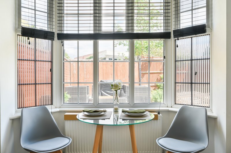 Dining nook with round table, two grey chairs and bay window overlooking garden