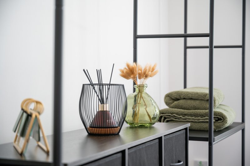 Modern console table with decorative items, flowers in vase, towels and window behind