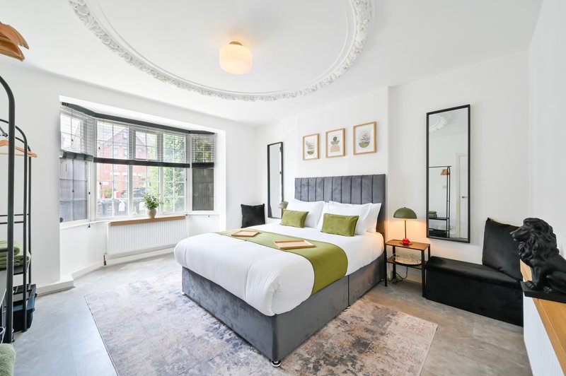 Bright modern bedroom with double bed, decorative ceiling rose, large window and mirror