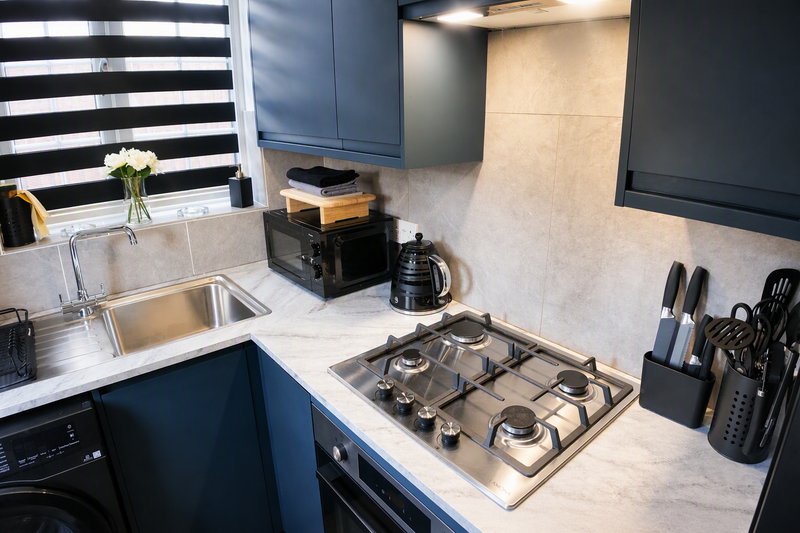 Modern kitchen with dark blue cabinetry, gas hob, stainless steel sink and marble countertop