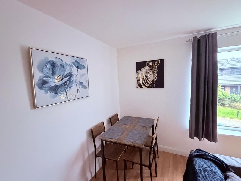 Dining area with wooden table, chairs, framed flower artwork and zebra print wall decor