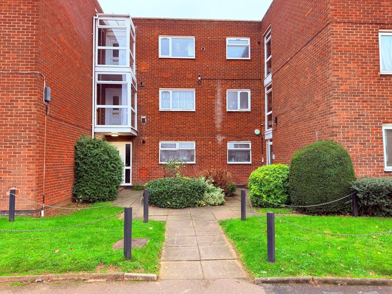 Red brick apartment building with manicured gardens, pathway and entrance door