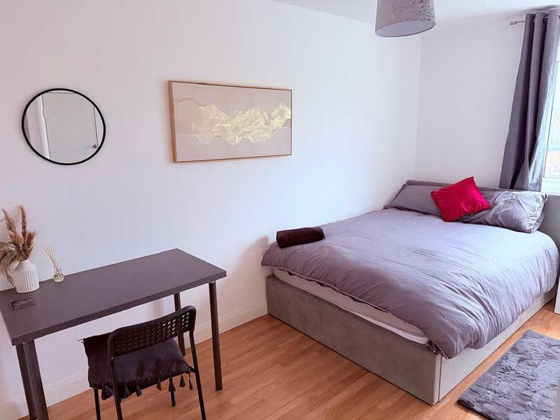Bedroom with double bed, desk, chair, wooden floor and wall art