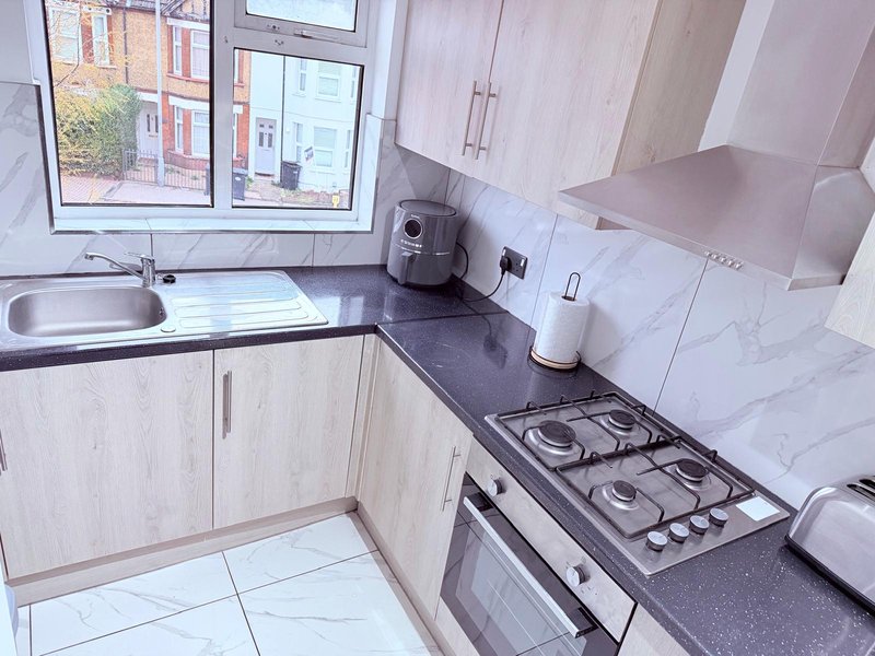 Modern kitchen with white cabinetry, gas hob, sink, and marble-effect backsplash