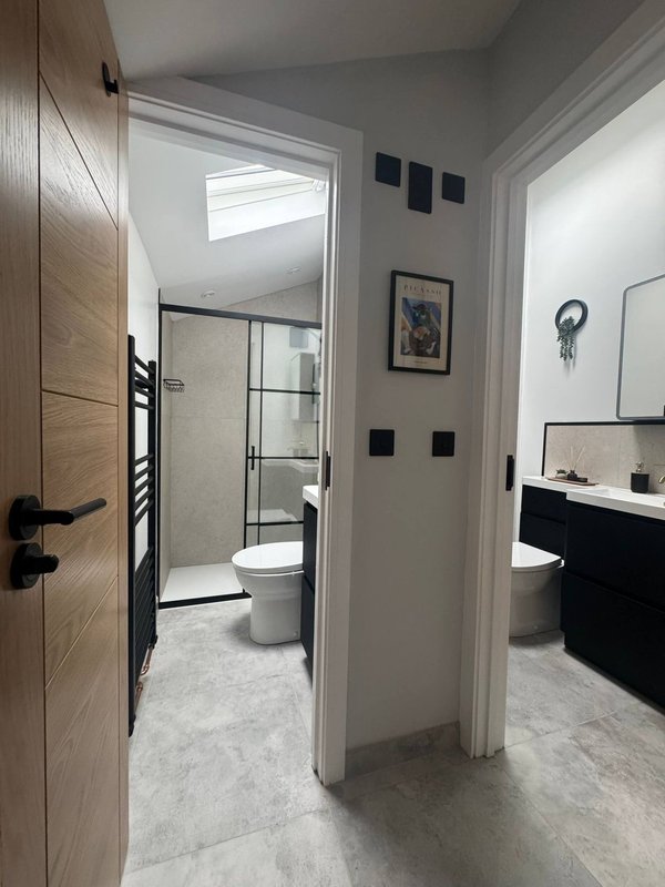 Modern bathroom with walk-in shower, toilet, and vanity sink with black fixtures