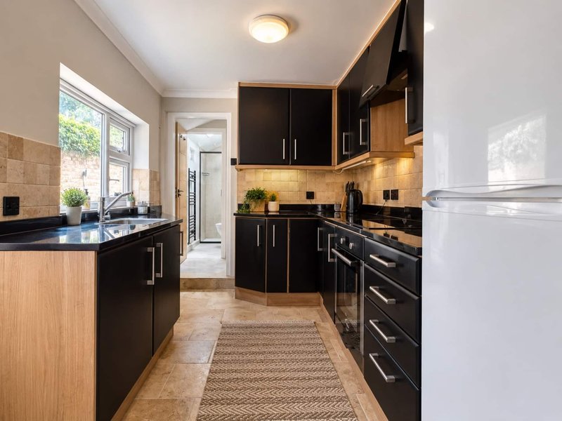 Modern kitchen with black cabinetry, blue countertops, tile backsplash and window overlooking garden