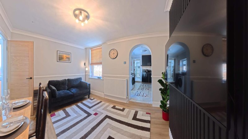 Bright living room with navy sofa, geometric rug, archway, and staircase to upper floor
