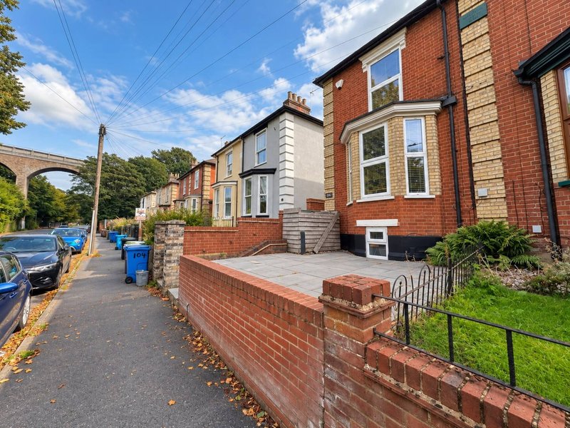 Brick terraced house exterior with front garden, driveway and street view