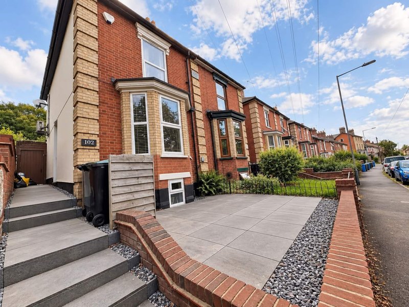 Brick semi-detached house with front garden, driveway and contemporary paving