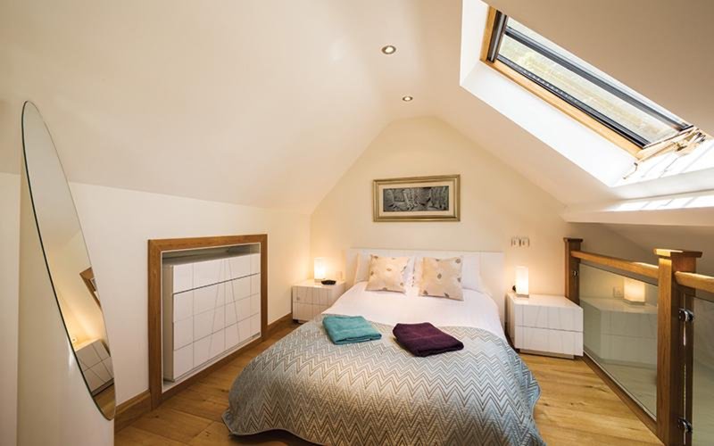 Attic bedroom with double bed, wooden floor, skylight and bedside lamps