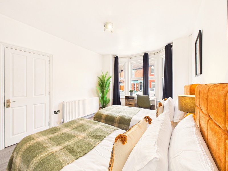 Bright bedroom with double bed, green striped bedding, wooden headboard and large window