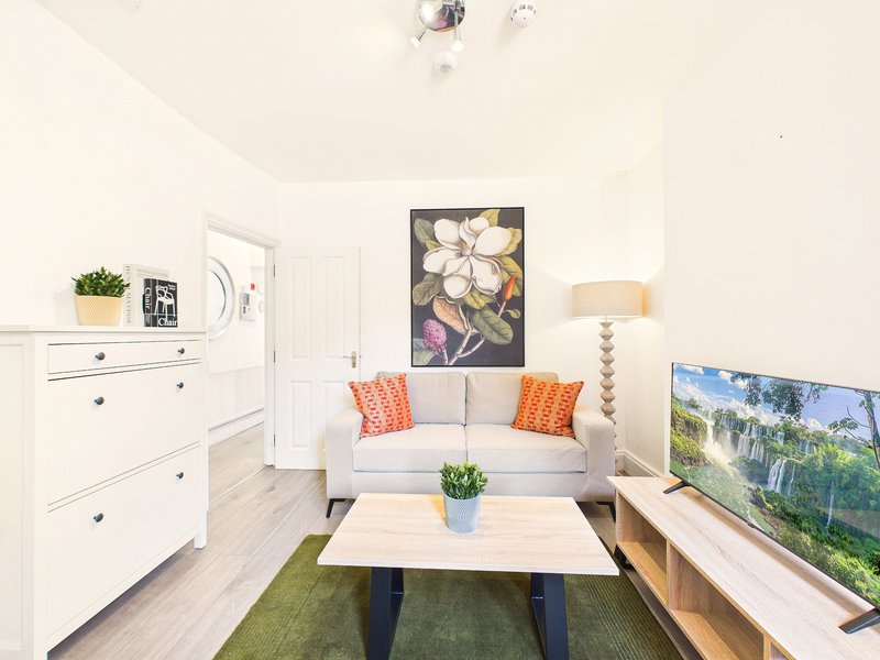 Bright living room with cream sofa, wooden coffee table, white dresser and wall art