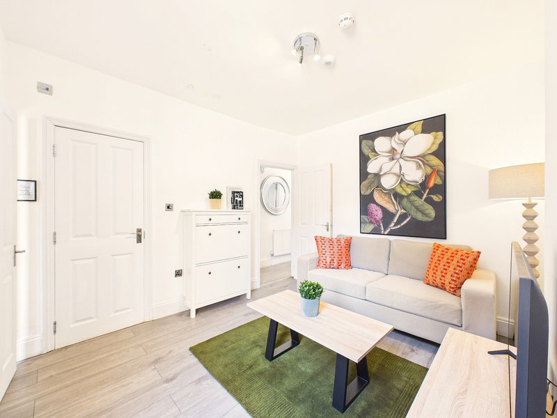 Modern living room with gray sofa, orange cushions, wooden coffee table, and floral wall art