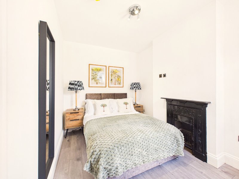 Bright bedroom with double bed, wooden nightstands, patterned lamps, and decorative wall art