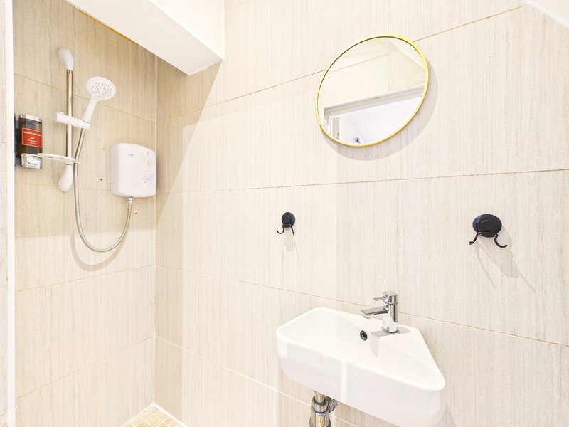 Modern bathroom with white sink, round mirror, shower head and wall-mounted accessories