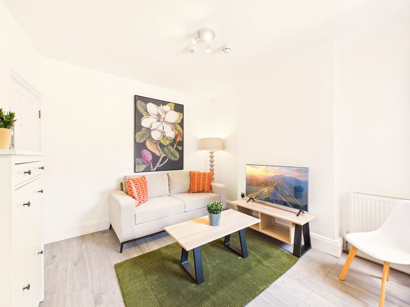 Bright living room with cream sofa, coffee table, TV stand, and wall art