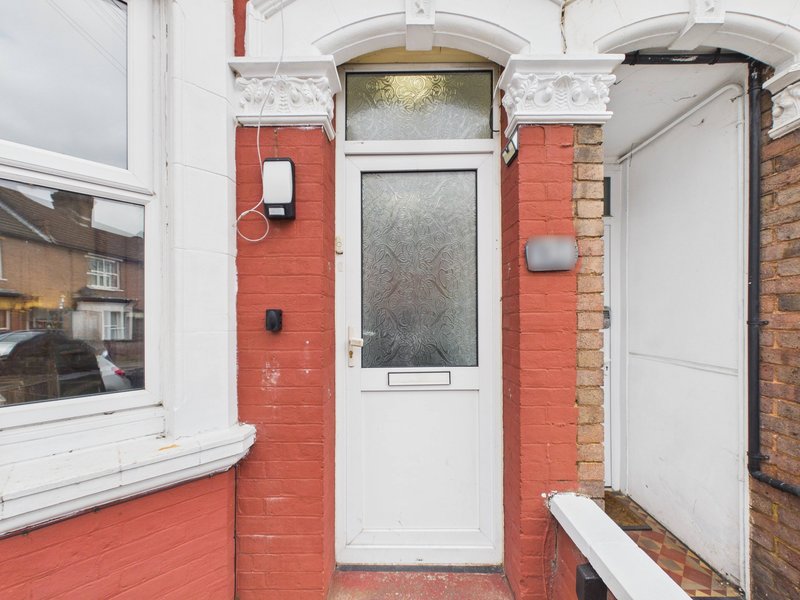 Red brick building exterior with white entrance door and window, residential street view
