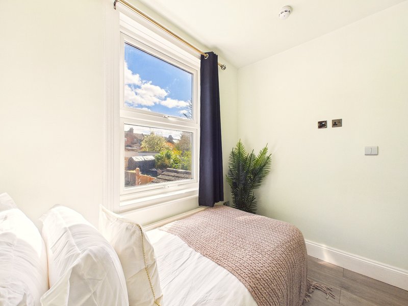Bright bedroom with double bed, large window with countryside view, and potted plant