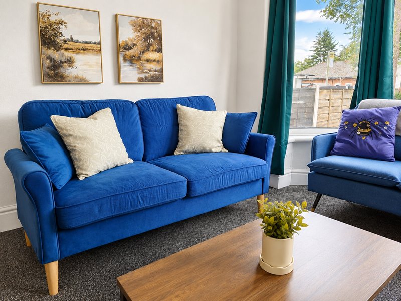 Bright living room with blue sofa, cream cushions, wooden coffee table and potted plant