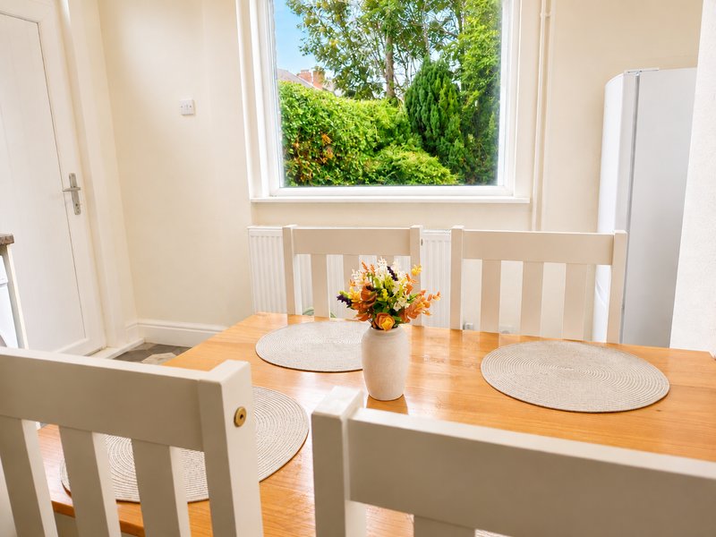 Bright dining room with wooden table, white chairs, flower arrangement and garden view