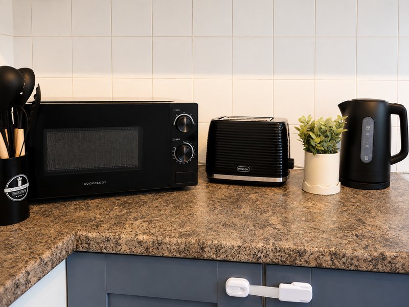 Kitchen countertop with microwave, toaster, kettle, small plant and kitchen utensils