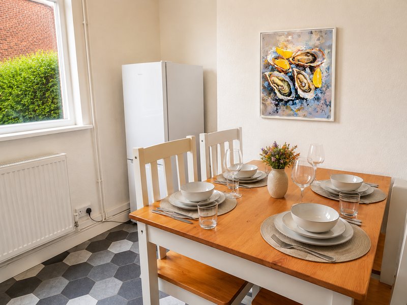 Dining room with wooden table, place settings, white chairs and window with green view