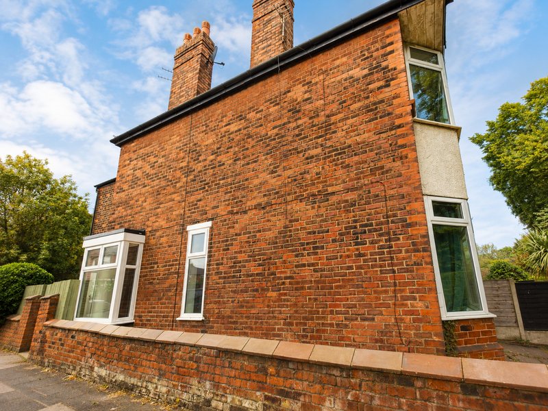 Brick semi-detached house exterior with bay window, chimneys and front garden