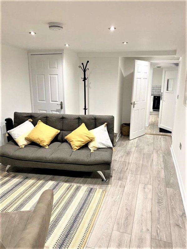 Modern living room with gray sofa, yellow cushions, striped rug and wood-effect flooring