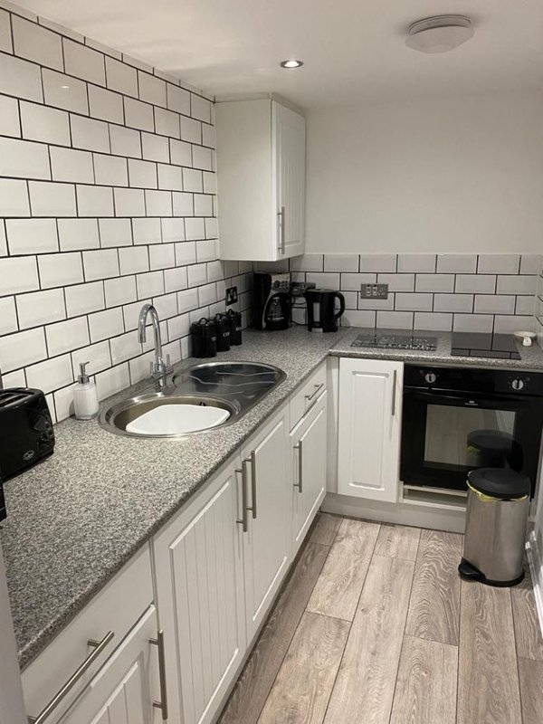Modern kitchen with white subway tile backsplash, grey countertop, white cabinetry and black appliances