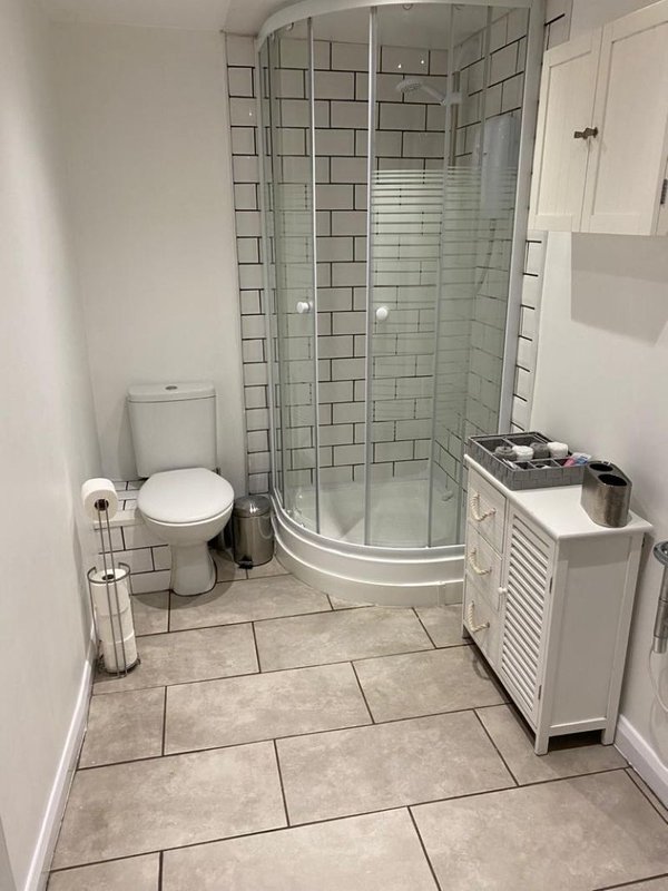 Modern bathroom with curved shower enclosure, white toilet, and tiled flooring