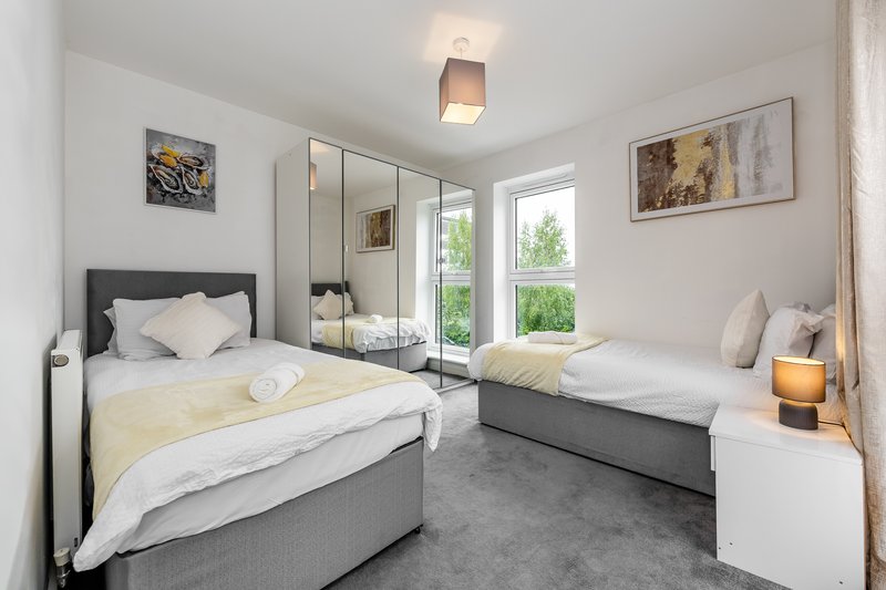 Bright twin bedroom with two single beds, mirrored wardrobe, window and ceiling light