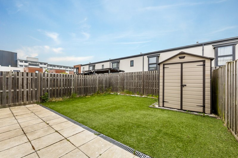 Fenced garden with paved patio, green lawn, and garden shed
