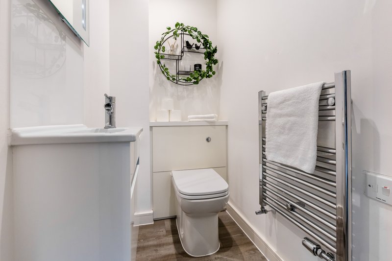Modern bathroom with toilet, sink, towel rail and decorative wreath on wall