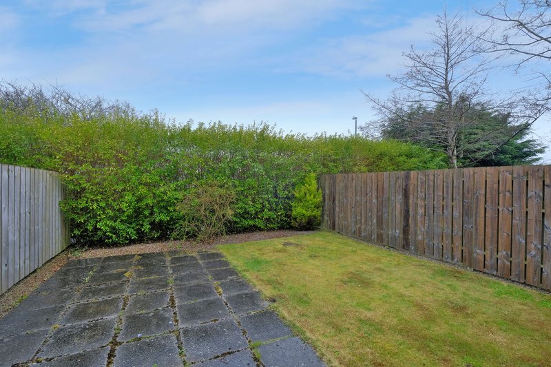 Enclosed garden with paved patio area, grass lawn, wooden fencing and hedge borders