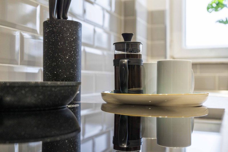 Kitchen counter styling with decorative vases, ceramic cups and a French press coffee maker